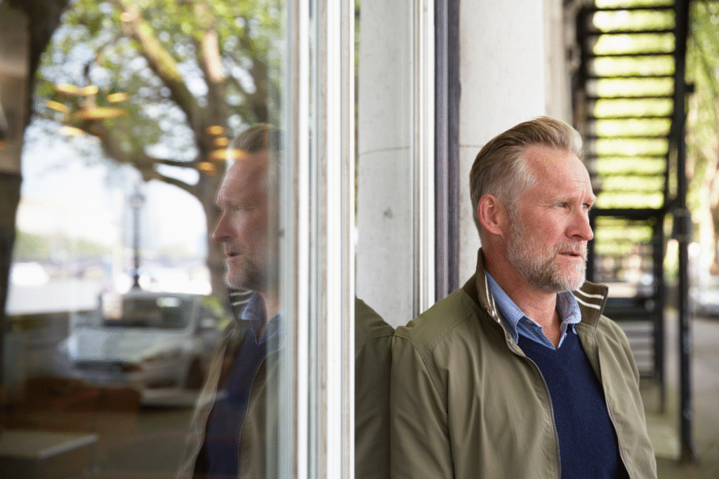 Person reflecting by a window in soft morning light, symbolizing midlife self inquiry