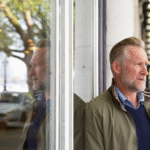 Person reflecting by a window in soft morning light, symbolizing midlife self inquiry
