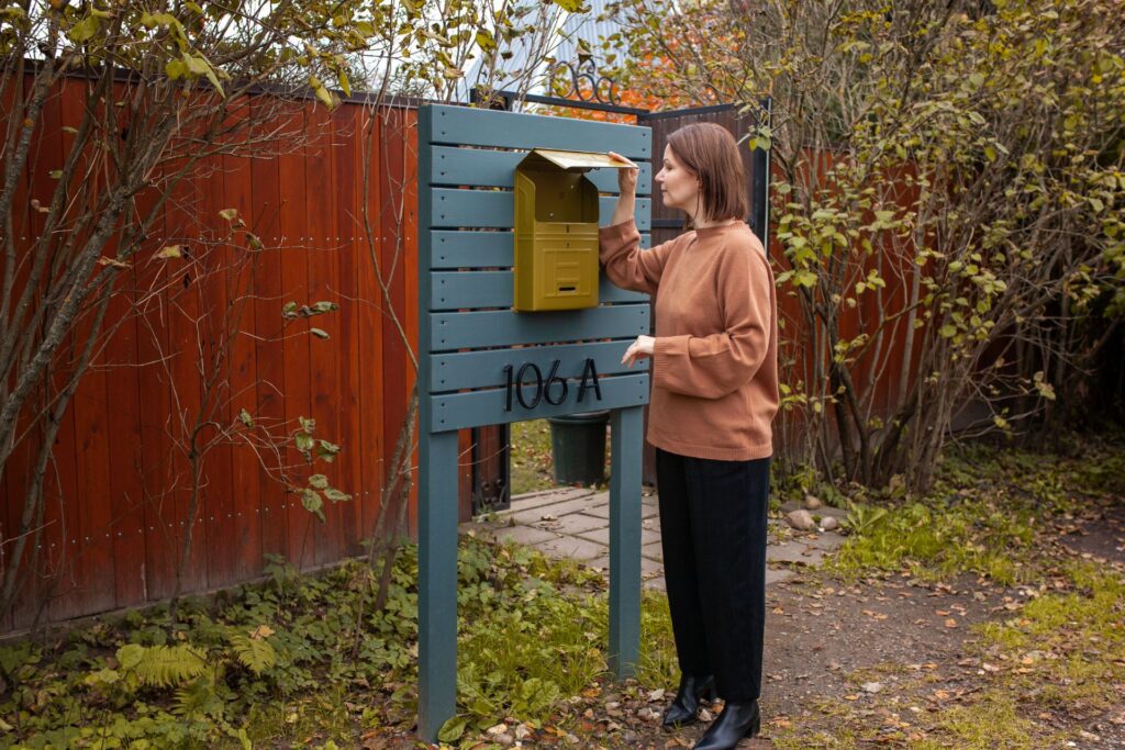 Woman standing at mailbox in quiet moment of midlife self-reflection and reinvention