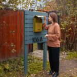 Woman standing at mailbox in quiet moment of midlife self-reflection and reinvention