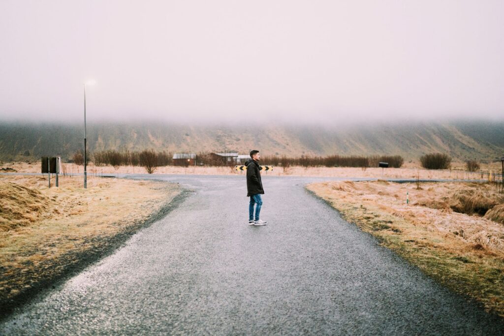 Person standing at a crossroads path representing a decision to break generational patterns