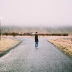 Person standing at a crossroads path representing a decision to break generational patterns